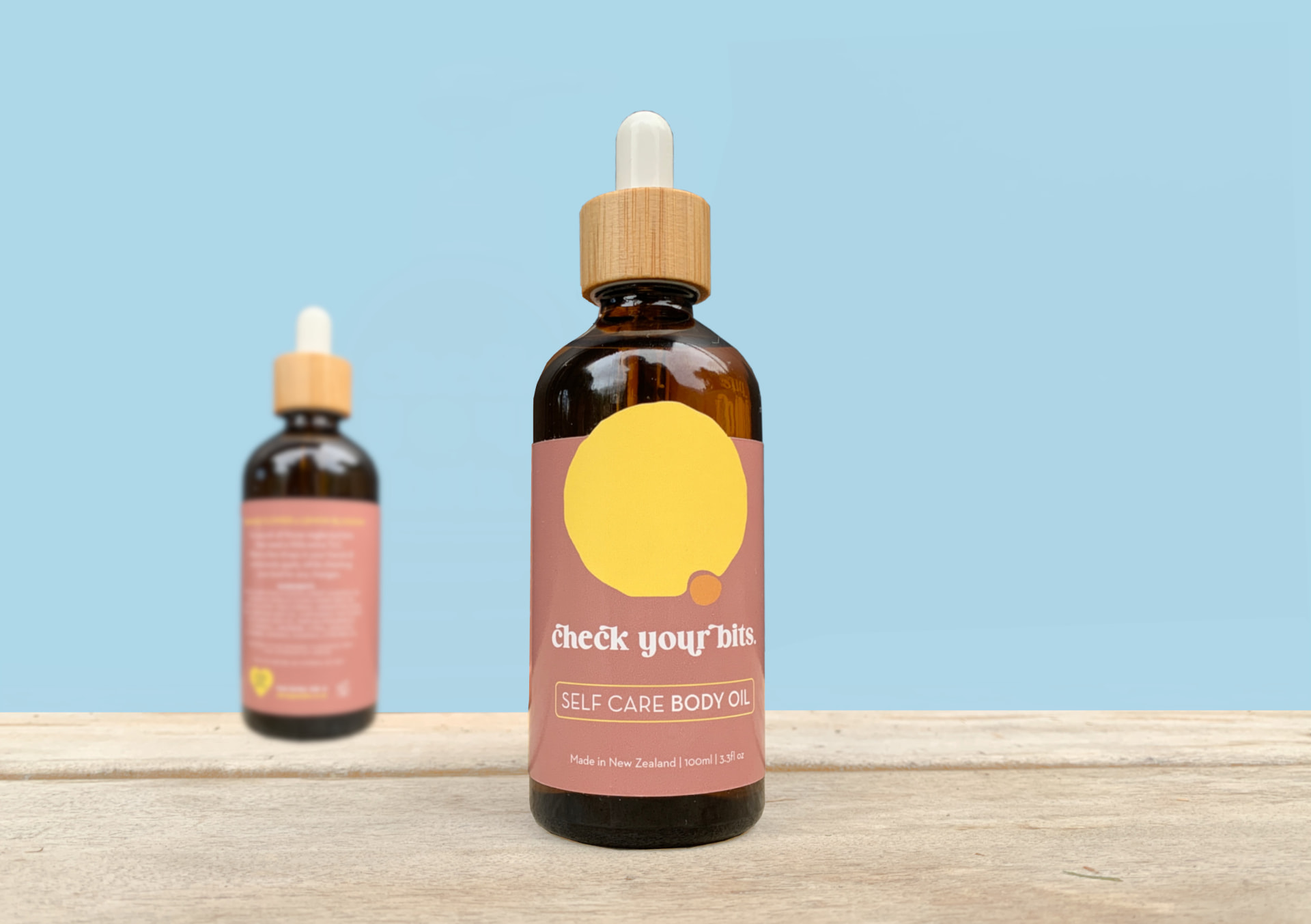 Check Your Bits self care body oil bottles on a wooden bench